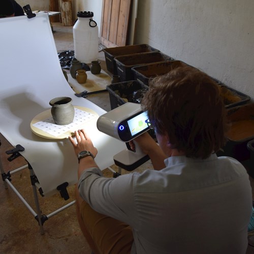 M. Košťál scanning a ceramic vessel decorated with a tracing wheel.