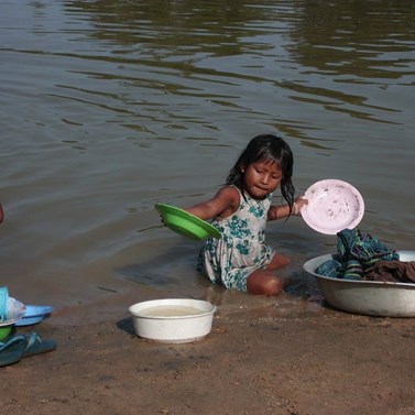 “Meprire”, děti, se učí pomáhat při denních aktivitách v rodinách, zde dívka pomáhající matce u řeky.
