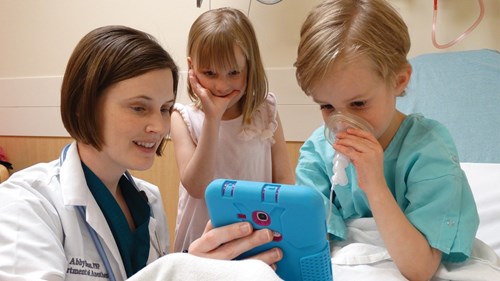 Anesteziolog vysvětluje dětskému pacientovi, jak bude dýchat do obličejové masky.