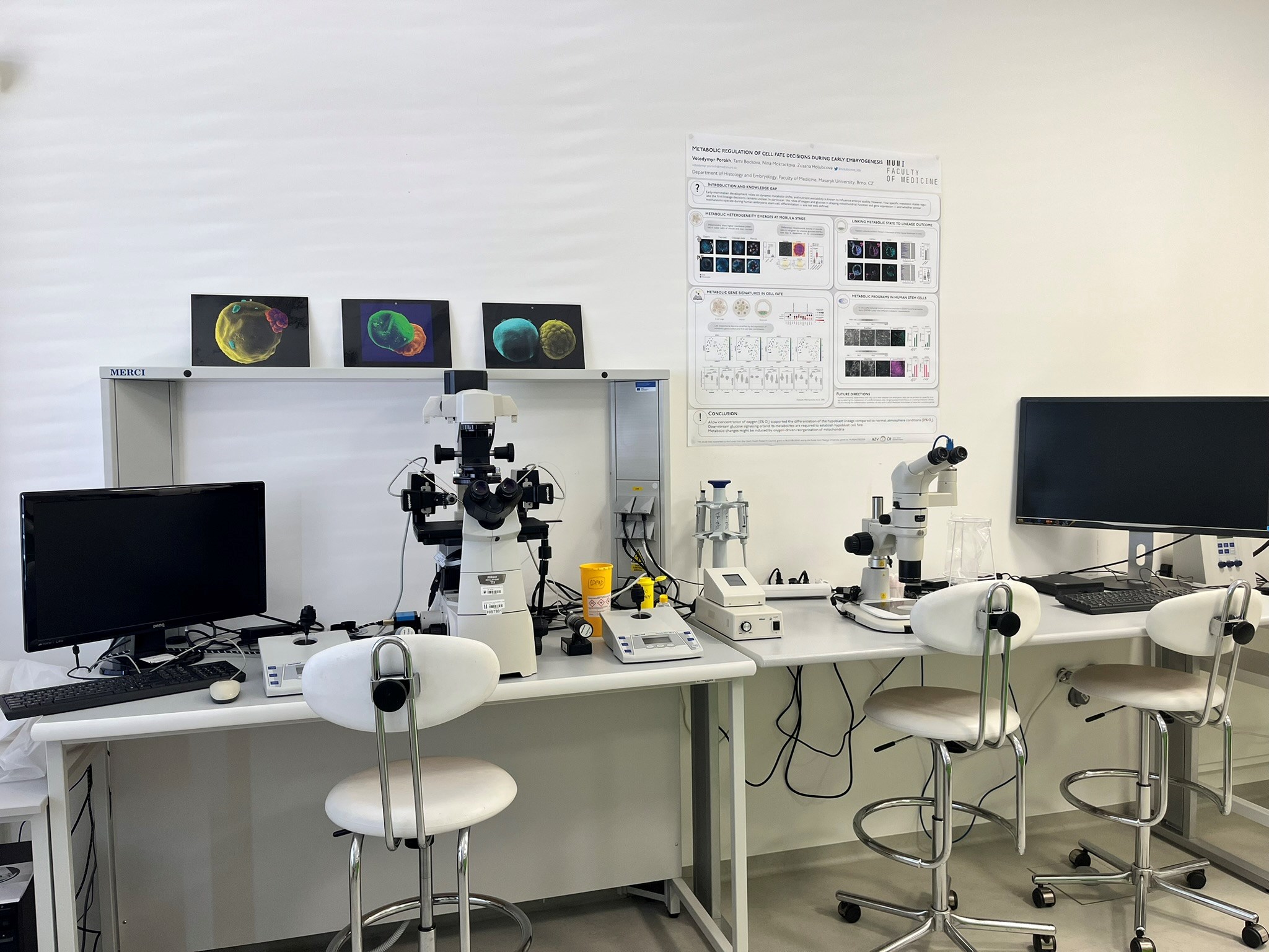 Laboratoř s mikroskopy, monitory a vědeckými obrázky na pozadí.