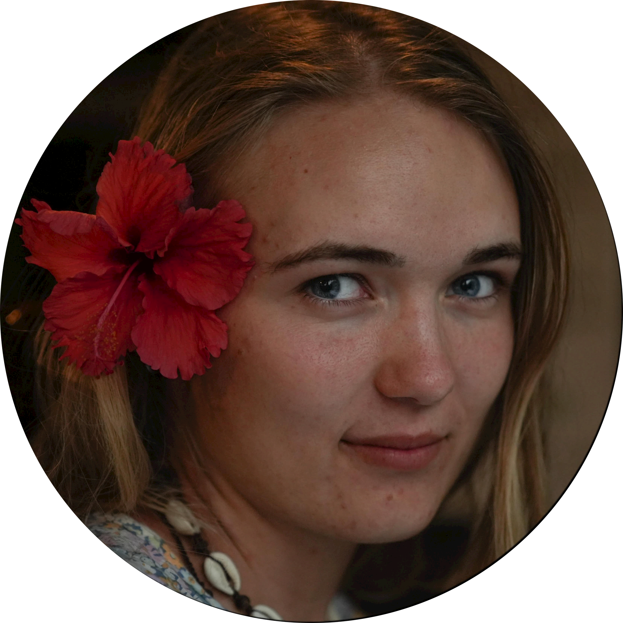 Detail snímku ženy s červeným květem v vlasech, pozadí a část obrazu je rozostřená.